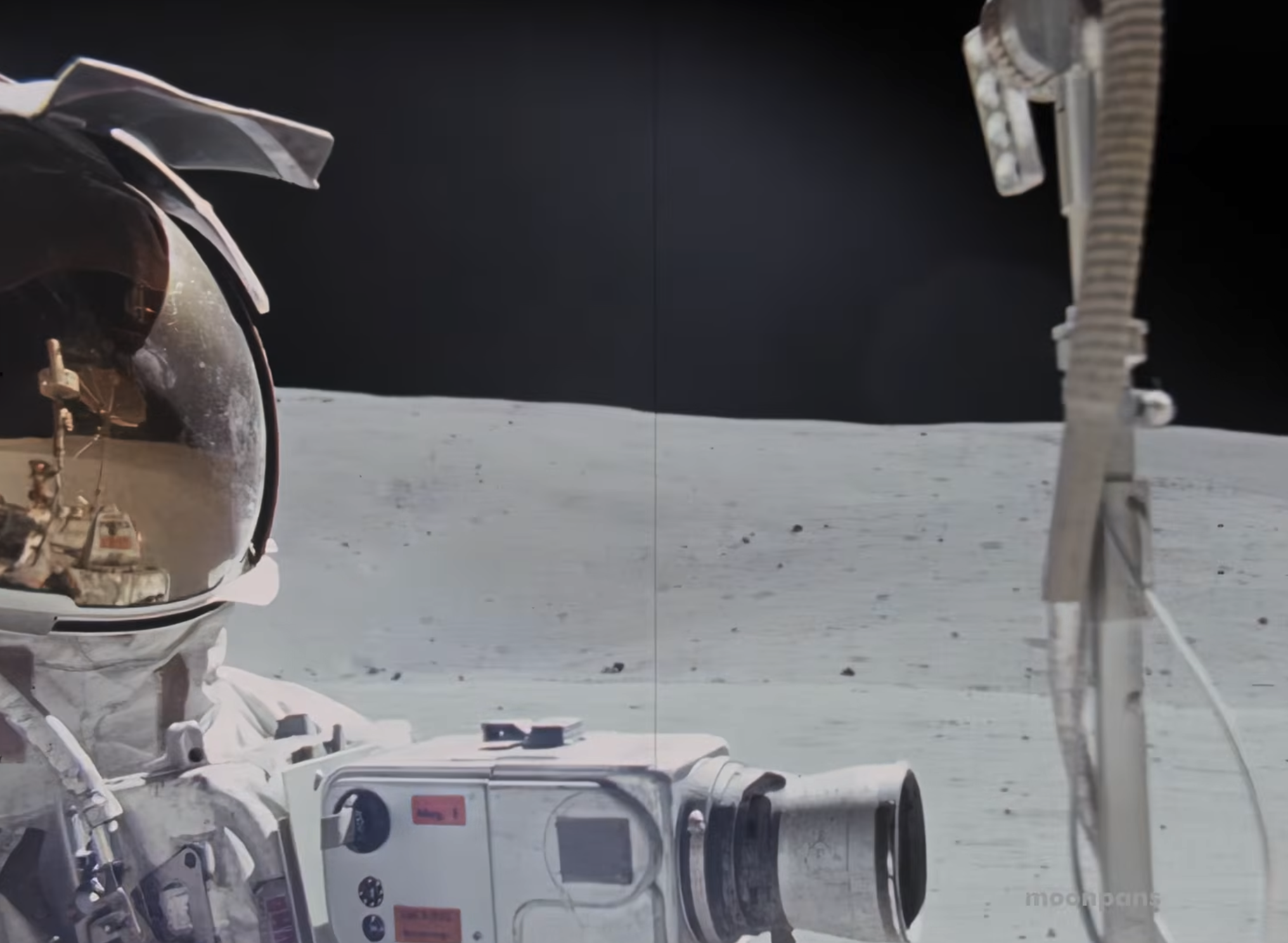 Un astronauta a bordo del vehículo lunar del Apolo 16, con equipo de filmación y la superficie lunar gris delante