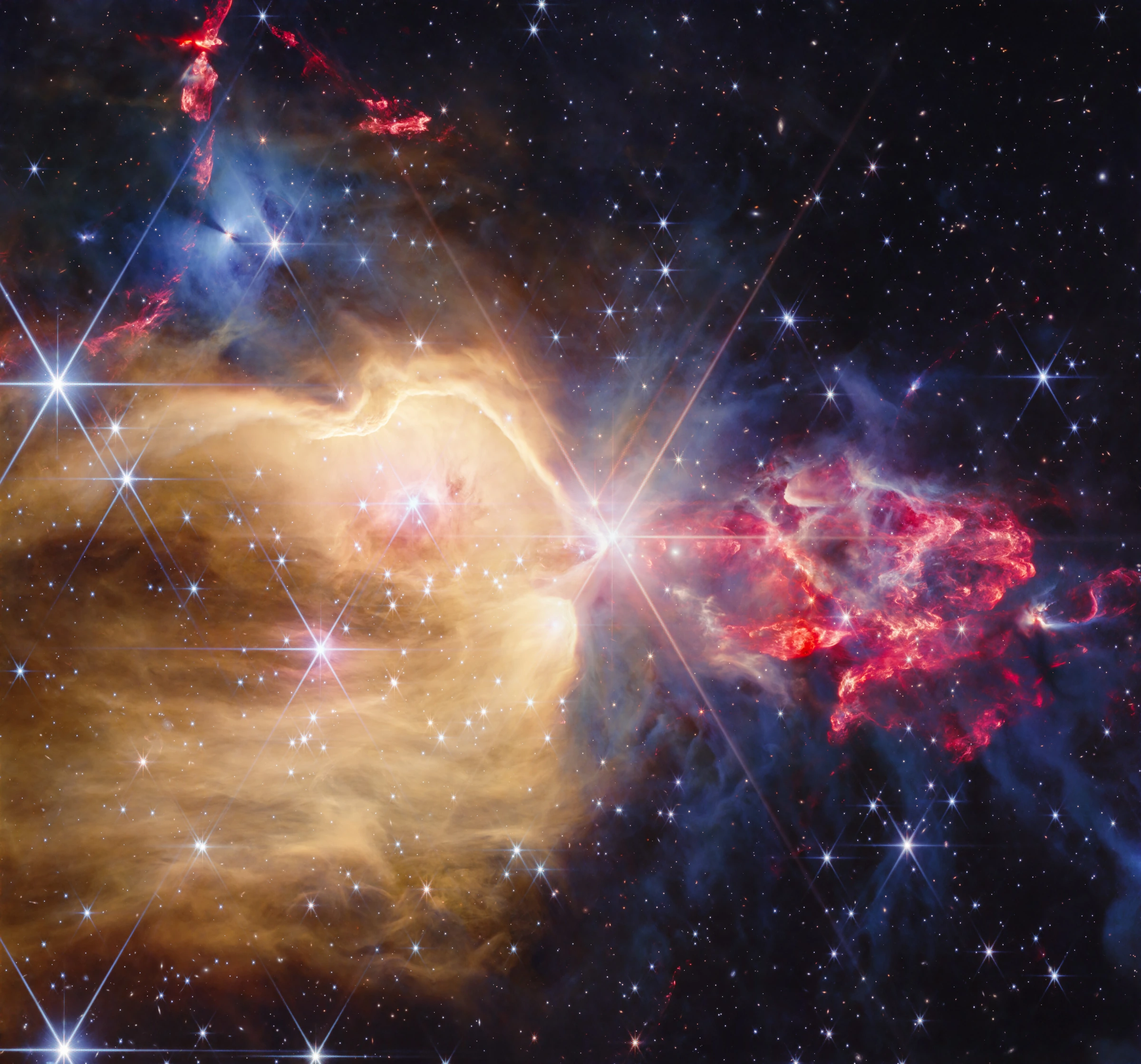 Webbs Aufnahme von NGC 7129 mit einem goldenen Hohlraum links des hellen Zentralsterns und roten Ausflüssen in blaugrauen Wolken rechts